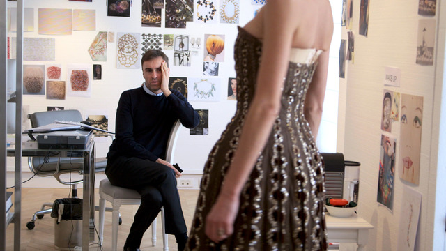 New Dior designer Raf Simons looks at a vintage Dior dress from the documentary DIOR & I, directed by Frederic Tcheng.