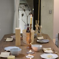 KIKOFのテーブルに器、中川木工芸のカトラリーや取り皿が並ぶ。キャンドルスタンドには、柔らかな色合いの大與の和ろうそく。穏やかな温もりを感じさせる食卓演出