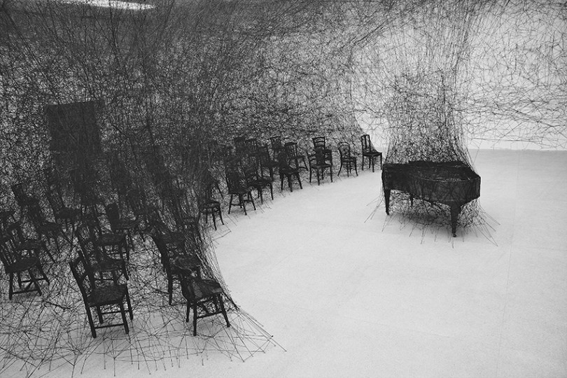 塩田千春 《静けさの中で》 2008年 焼けたピアノ、焼けた椅子、黒毛糸 展示風景：「存在様態」パスクアートセンター（スイス、ビール／ビエンヌ）2008年 撮影：Sunhi Mang