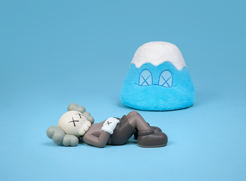 左：「KAWS:HOLIDAY JAPAN 9.5インチ ビニールフィギュア」ブラウン（約24cm 各2万1,700円）、右：「KAWS:HOLIDAY JAPAN 富士山 8インチ ぬいぐるみ（シリアル番号証明書付き）」ブルー（約21cm 1万9,600円）